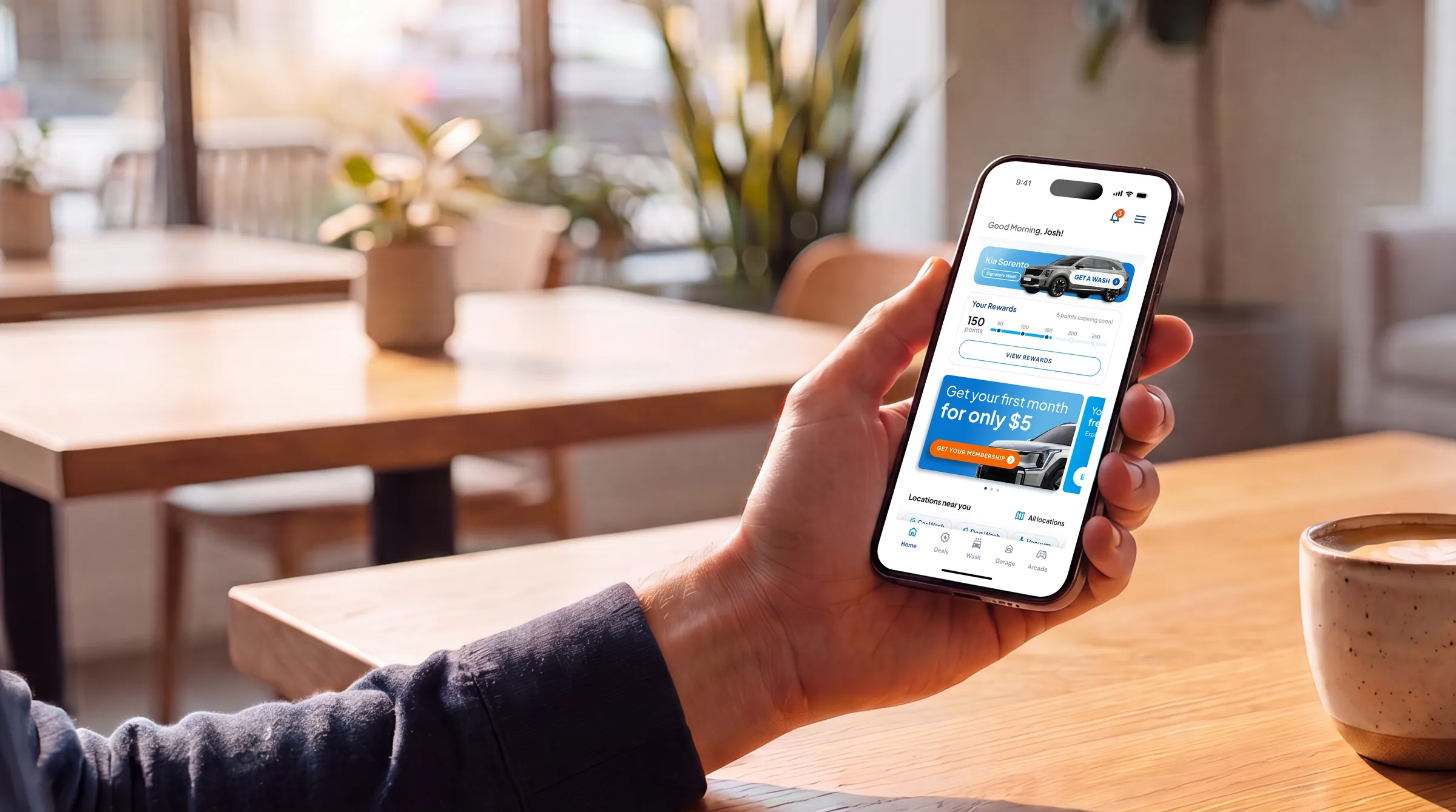 A wash member reviewing their vehicles in the AMP app over coffee